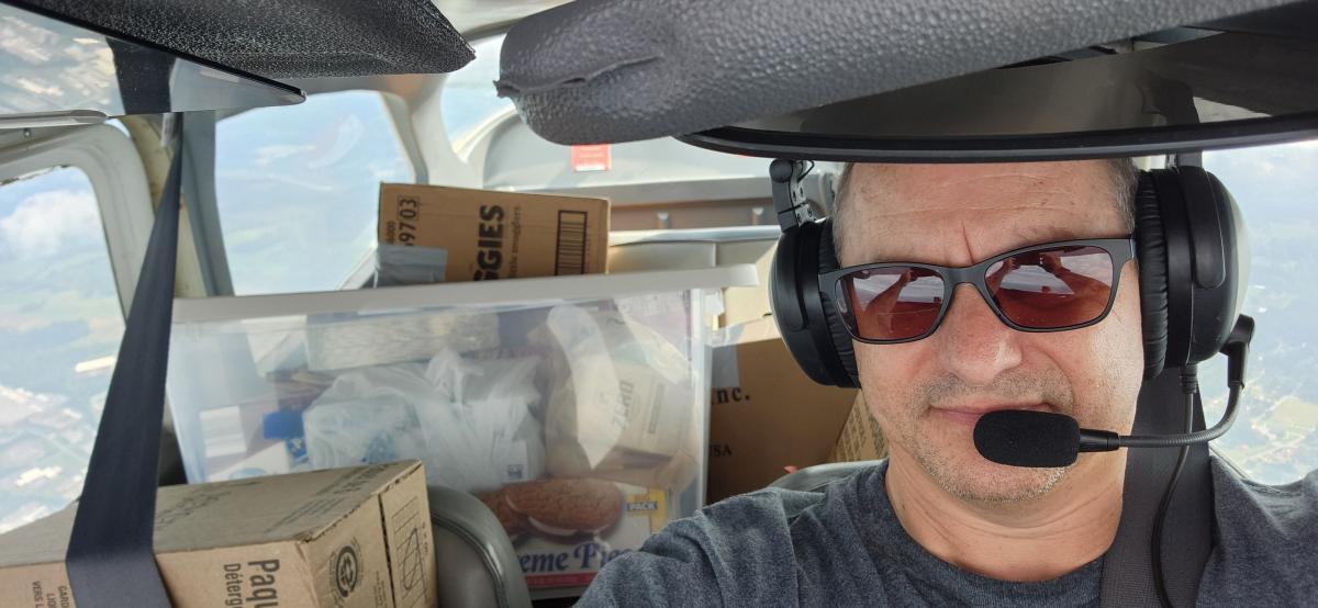 Gary Weissel takes a photo of him midflight with supplies in the back of his plane.
